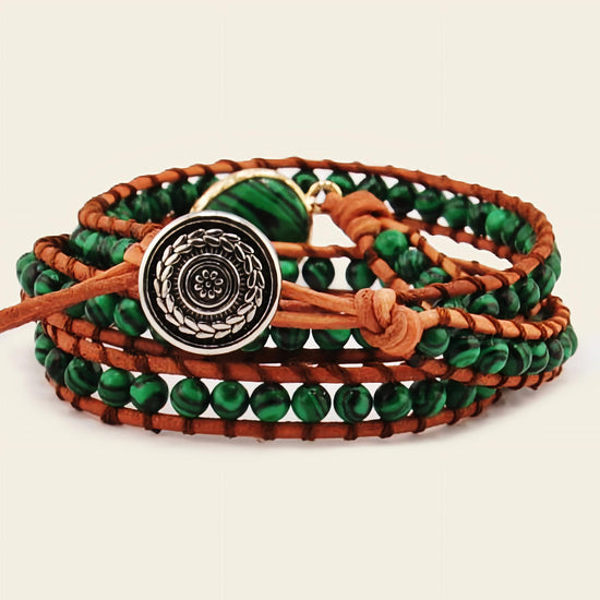 Multistrand bracelet with green beads and a decorative button clasp on a beige background