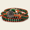 Multistrand bracelet with green beads and a decorative button clasp on a beige background
