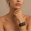 Close-up of a woman's neck and shoulder with a green beaded bracelet on a beige background