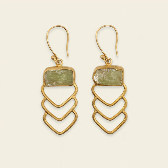 Gold earrings with green stone on a beige background