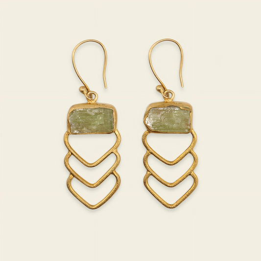 Gold earrings with green stone on a beige background