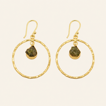 Gold hoop earrings with green stones on a beige background
