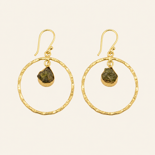 Gold hoop earrings with green stones on a beige background
