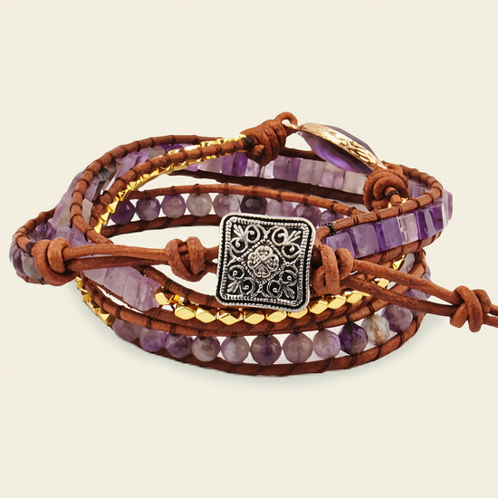 Multistrand bracelet with purple beads, brown leather, and a silver charm on a beige background
