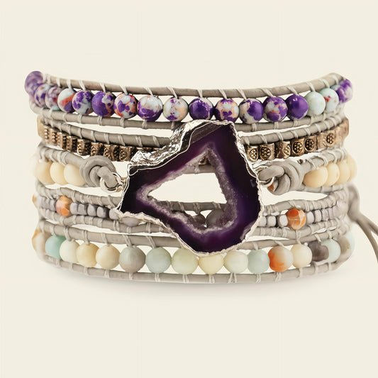 Stack of colorful beaded bracelets with a purple agate stone on a light background