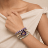 Hand wearing multiple bracelets with a neutral background