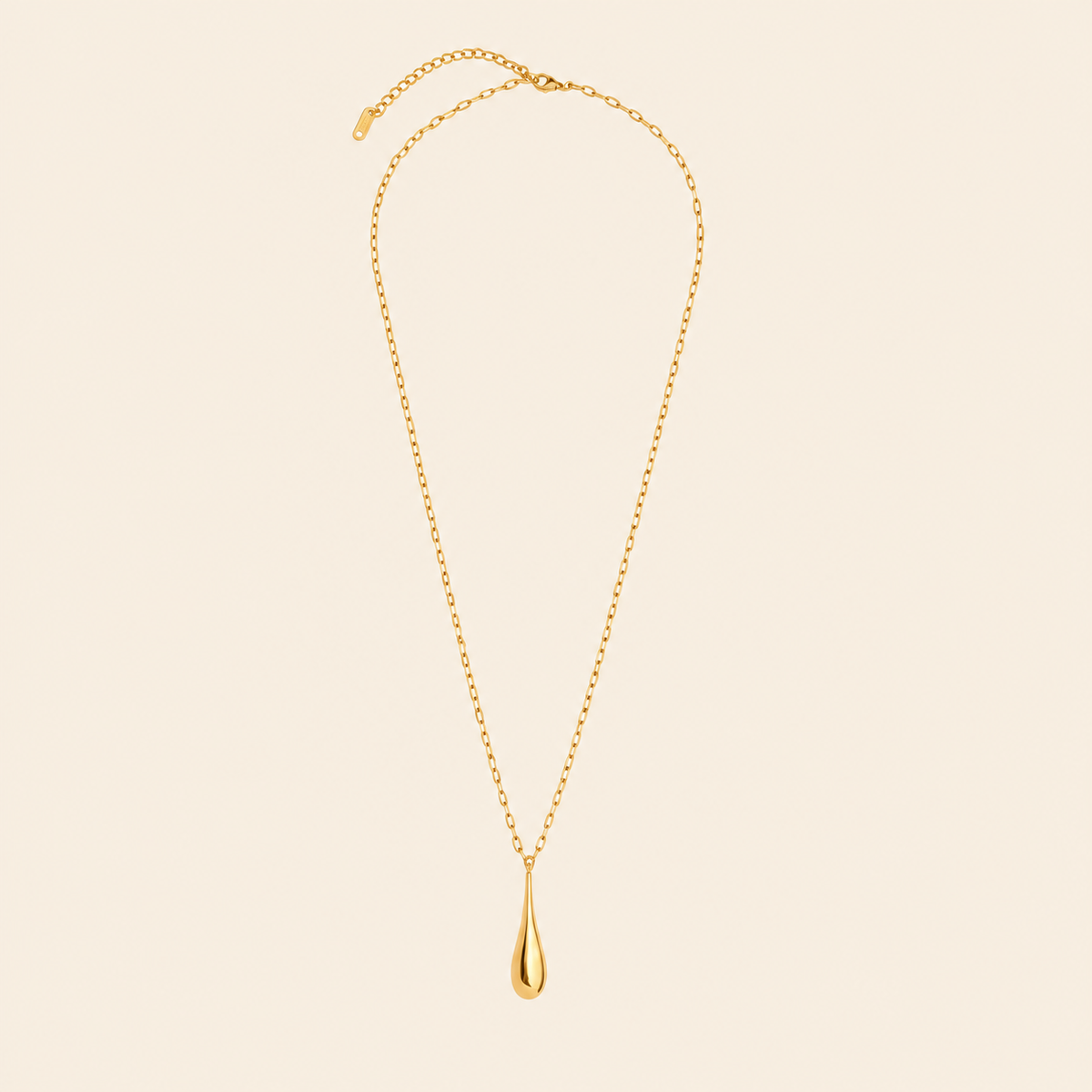 A delicate gold chain necklace with a polished teardrop pendant, displayed against a solid light beige background.