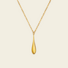 A polished gold teardrop pendant necklace on a delicate gold chain, presented against a solid, warm off-white background.