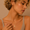 Woman wearing a gold necklace against a beige background