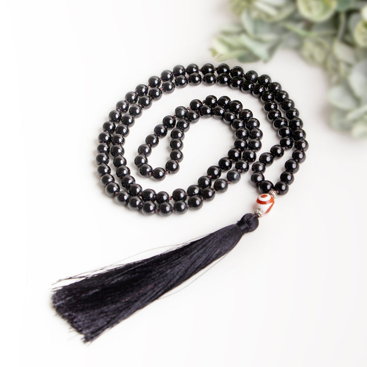 Handcrafted black beaded necklace with long black tassel and single orange accent bead