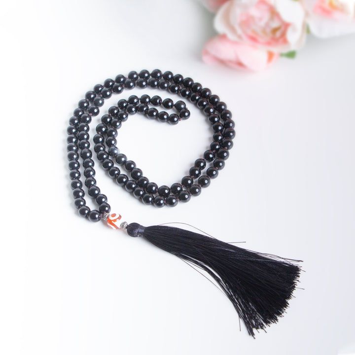 Handmade black onyx beaded necklace featuring a long black tassel and single orange accent bead
