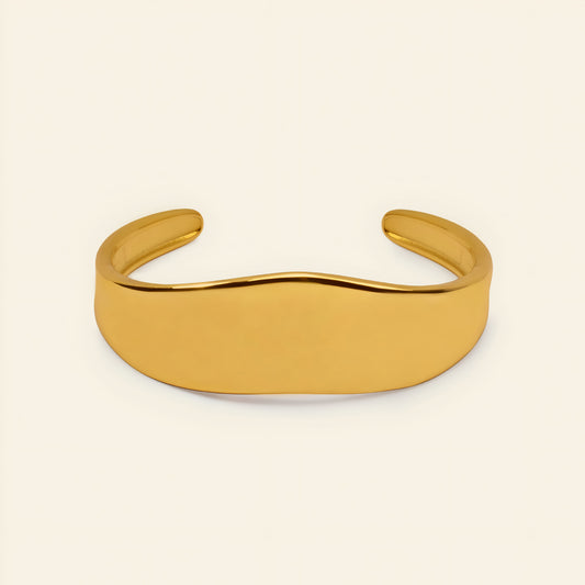 Crest Band Cuff with a broad polished band with a wavy edge in gold finish