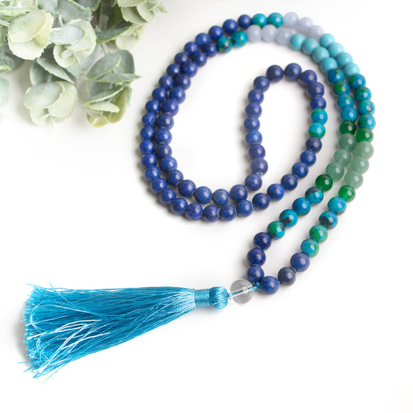 Close-up of handmade beaded necklace with gradient blue and green stones and a bright turquoise tassel