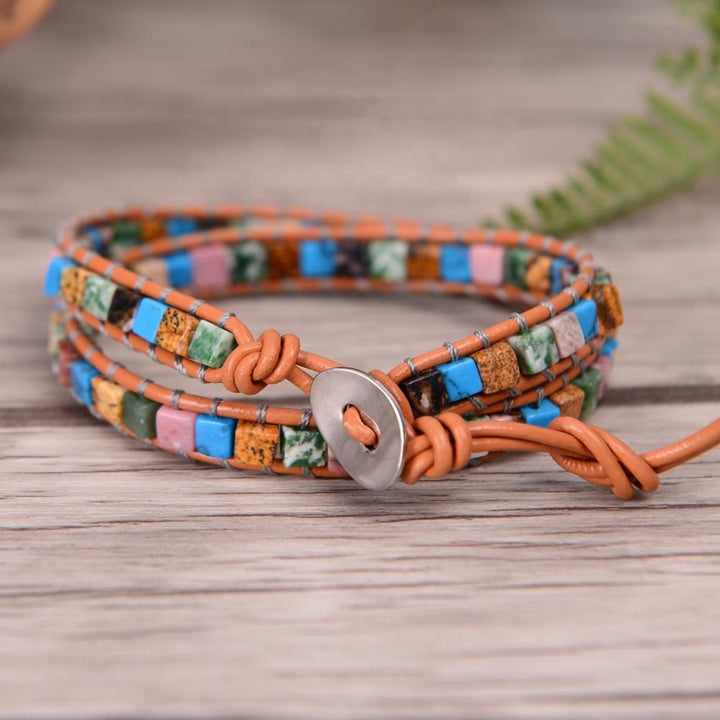 Adjustable handmade 2-layer wrap bracelet showcasing a colorful mix of natural cubic stones in turquoise, pink, green, brown, and black hues, braided with tan leather and silver thread. Finished with a secure silver button closure, this bohemian piece combines durability, comfort, and vibrant style perfect for everyday wear or gifting.