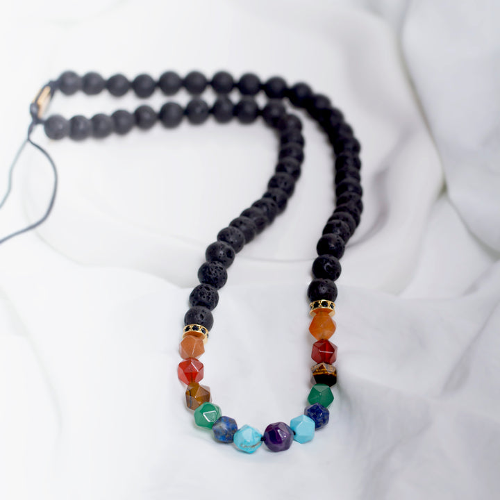Handmade necklace featuring black lava beads and multicolour natural stones in red, blue, green, and orange tones.