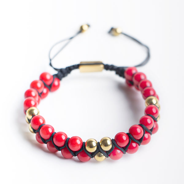 Close-up of a handmade red beaded bracelet with black cord and gold accent beads