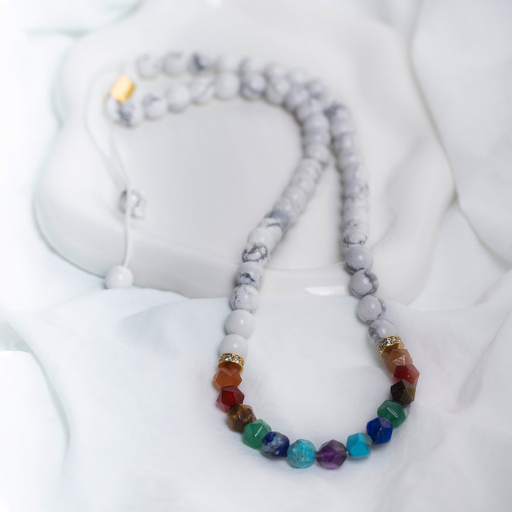 Handmade necklace with white howlite-style beads and multicolour faceted stones in rainbow tones, featuring gold accents and adjustable cord.
