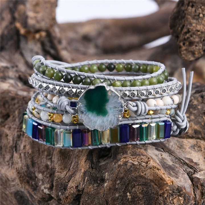 Handmade adjustable bracelet featuring a natural moss agate slice, green beads, metallic accents, and colourful stones in a layered design, perfect for boho jewellery lovers.