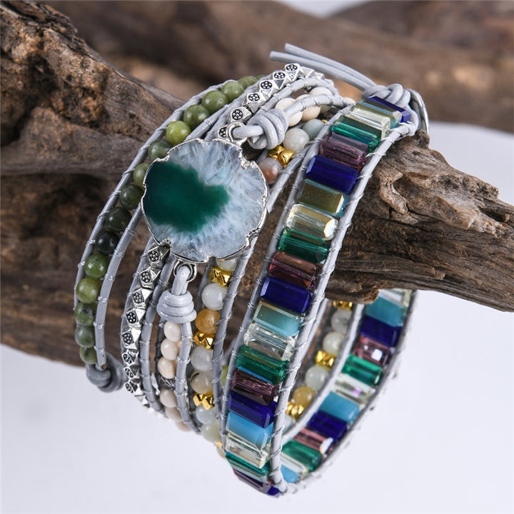 Handmade adjustable bracelet featuring a natural moss agate slice, green beads, metallic accents, and vibrant stones in a layered design, ideal for boho jewellery enthusiasts.