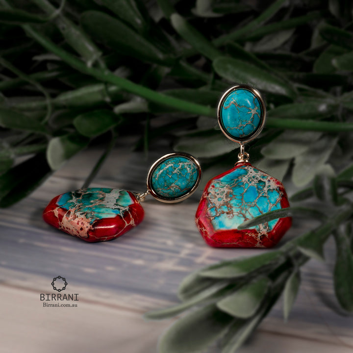 Gold-plated boho drop earrings featuring vibrant red and turquoise gemstone cabochons with natural veining, adding a bold and colorful touch to any outfit.