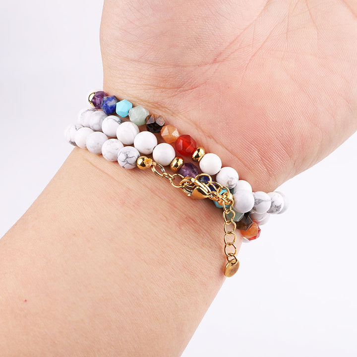 Handmade 7 chakra natural stones necklace/bracelet with white howlite beads, colorful gemstones, and gold accents, worn on the wrist.