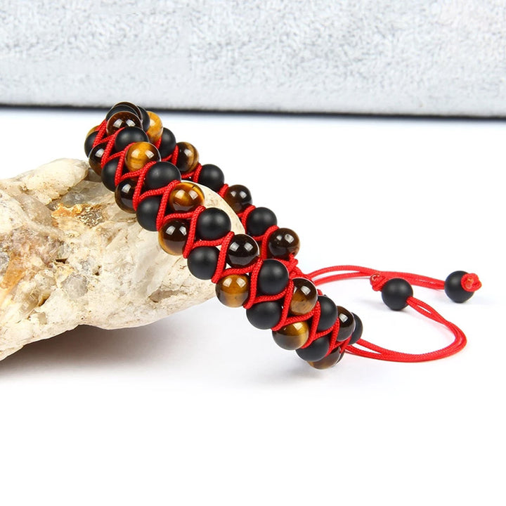 Handmade bracelet featuring black onyx and tiger eye stone beads, woven with red cord for an adjustable fit.