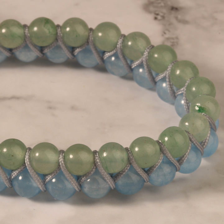 Close-up of a handmade bracelet featuring green aventurine and blue jade beads, woven with a grey cord for a soft and elegant look.