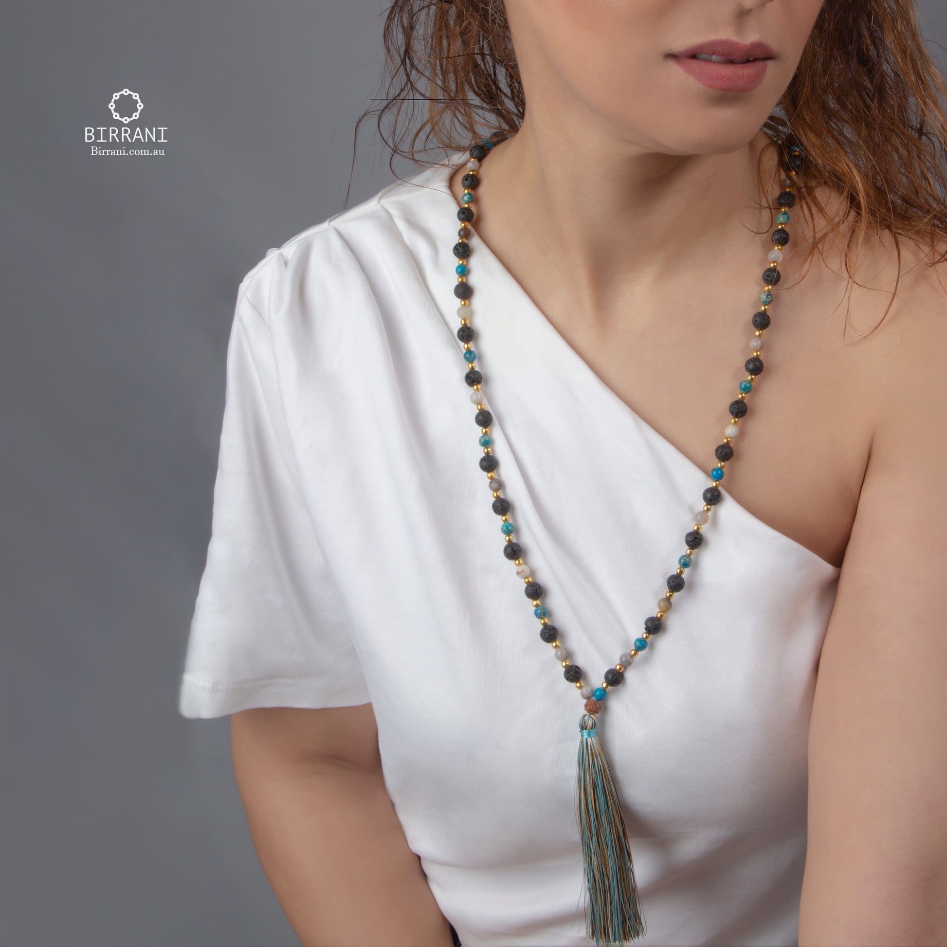 Handmade lava stone necklace with turquoise and gold accents, featuring a tassel, perfect for meditation and yoga practices.