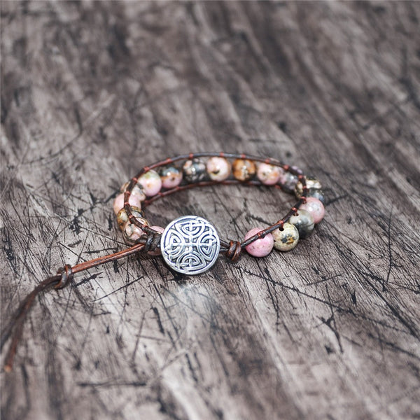 Handmade adjustable bracelet featuring natural rhodonite beads and a decorative Celtic button, offering a unique and earthy design.