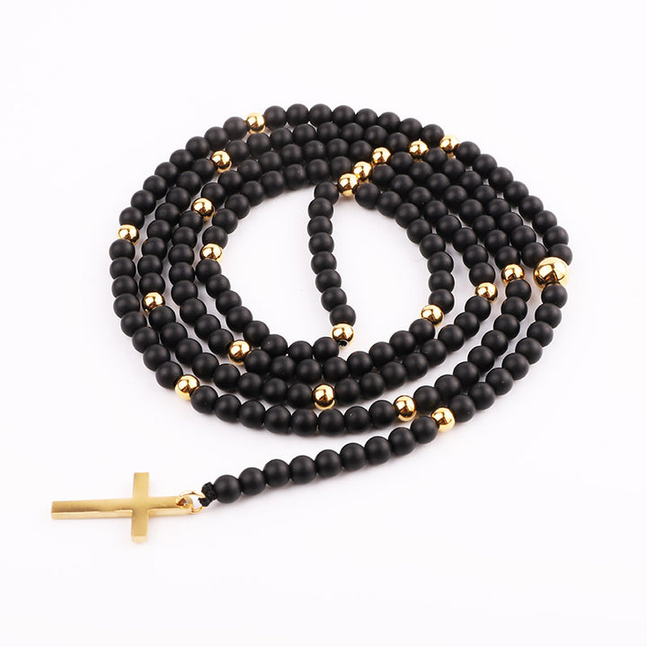 Handmade necklace with matte black beads and gold accents, featuring a gold cross pendant.