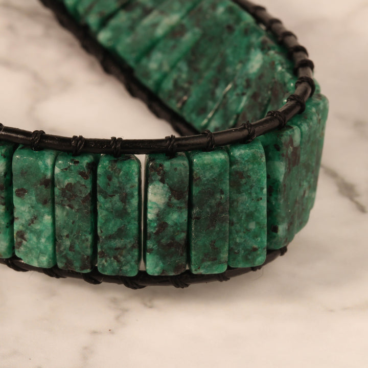 Adjustable leather wrap bracelet featuring natural green Serpentine stone tube beads, with a secure clasp, perfect for both casual and formal wear.