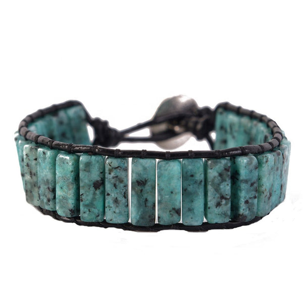 Close-up of a handmade adjustable bracelet featuring Serpentine tube stones in turquoise and black, with a leather cord and metal clasp.