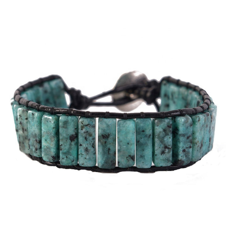 Close-up of a handmade adjustable bracelet featuring Serpentine tube stones in turquoise and black, with a leather cord and metal clasp.