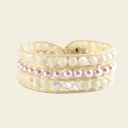 This handcrafted pearl wrap bracelet by Birrani features lustrous cream shell beads and a row of pale pink pearls, intricately woven onto a secure cord for comfort. Designed with timeless elegance and soft, natural tones, this three-layer bracelet is a perfect choice for women who love classic, artisan jewellery and want a beautiful piece to wear for special occasions or daily style.